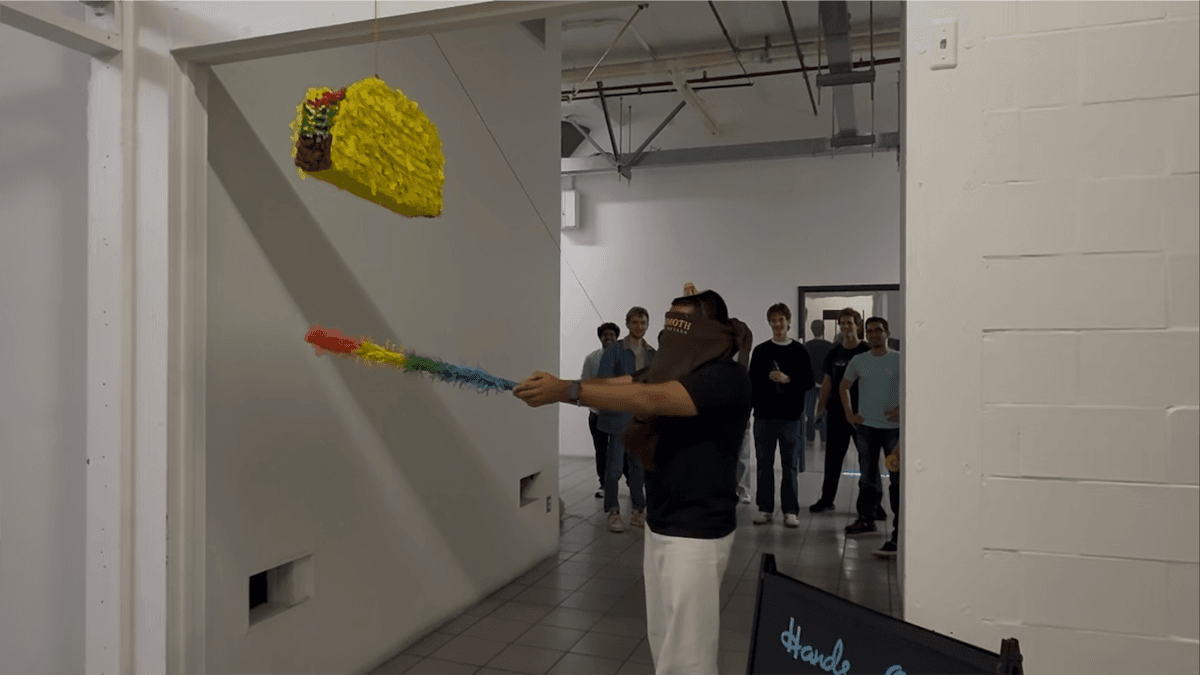 A teammate trying to hit a taco piñata while the team watches